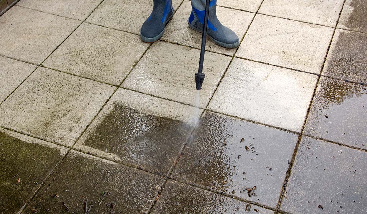 a high pressure water nozzle being used to clean outdoor stone tiles