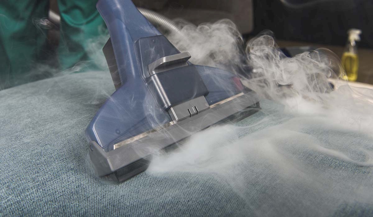 a steam cleaner removing stains from an upholstered couch